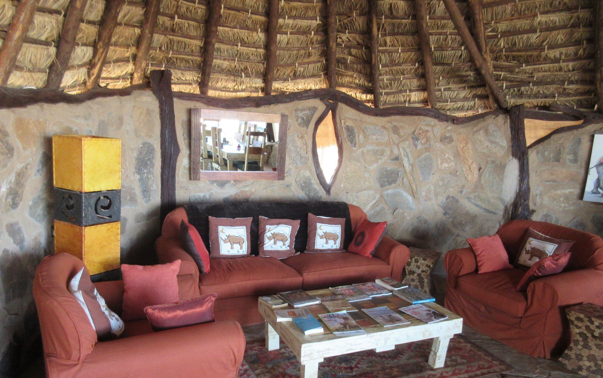 Una habitación acogedora con pared de piedra, techo de paja y un conjunto de sofás.