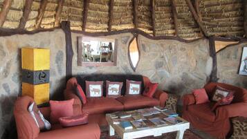 Una habitación acogedora con pared de piedra, techo de paja y un conjunto de sofás.