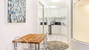Une cuisine moderne avec des meubles blancs, une table à manger en bois et un tapis gris.