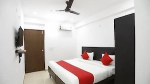 A hotel room with a bed, a ceiling fan, a TV mounted on the wall, and a door. - Coco TreeHotel (Gurugram)
