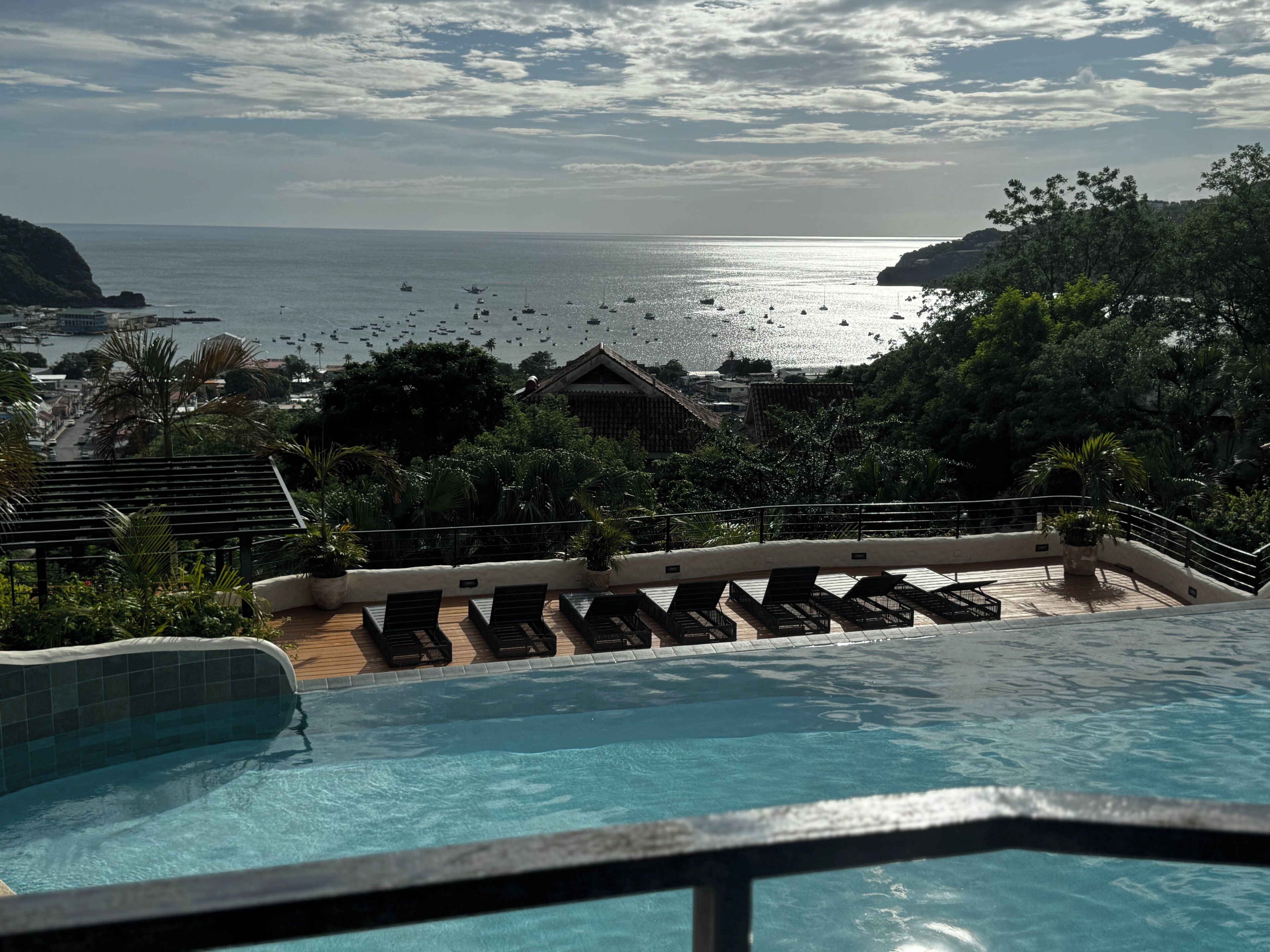 Piscina con sillones de descanso y vista al mar.