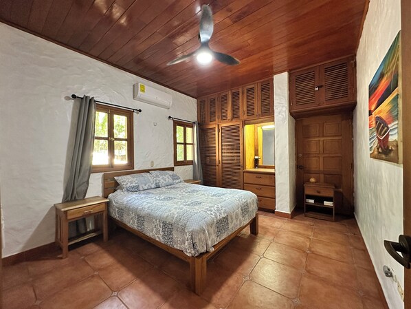 Un dormitorio con cama, armario de madera y ventilador de techo.