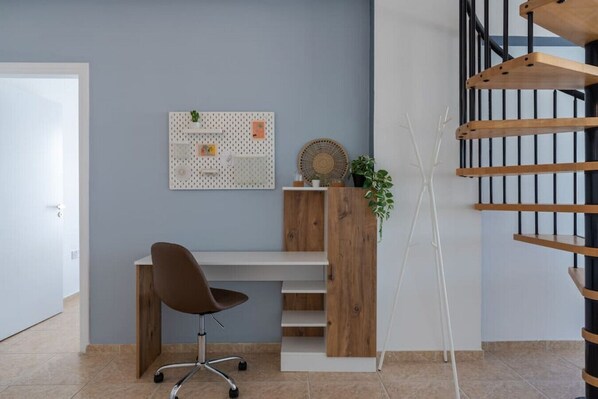 Un espace de bureau moderne avec un bureau, une chaise et une étagère, le tout placé contre un mur bleu.