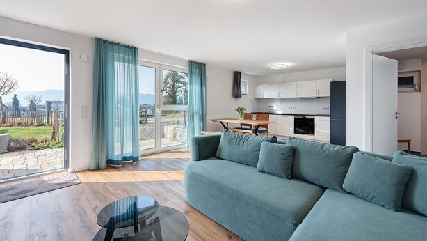 Una sala de estar moderna con un sofá, una mesa de centro de vidrio y vistas al exterior.