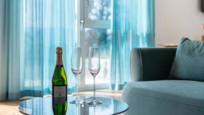 Una habitación con una mesa de vidrio, una botella de champán y dos copas.