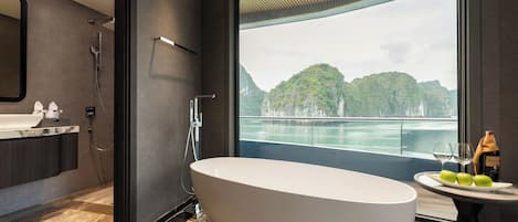 A modern bathroom with a freestanding bathtub, a large mirror, and a view of a natural landscape through a large window.