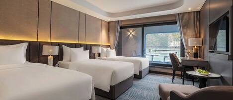 A hotel room with two beds, a desk, a chair, and a view of the sea.