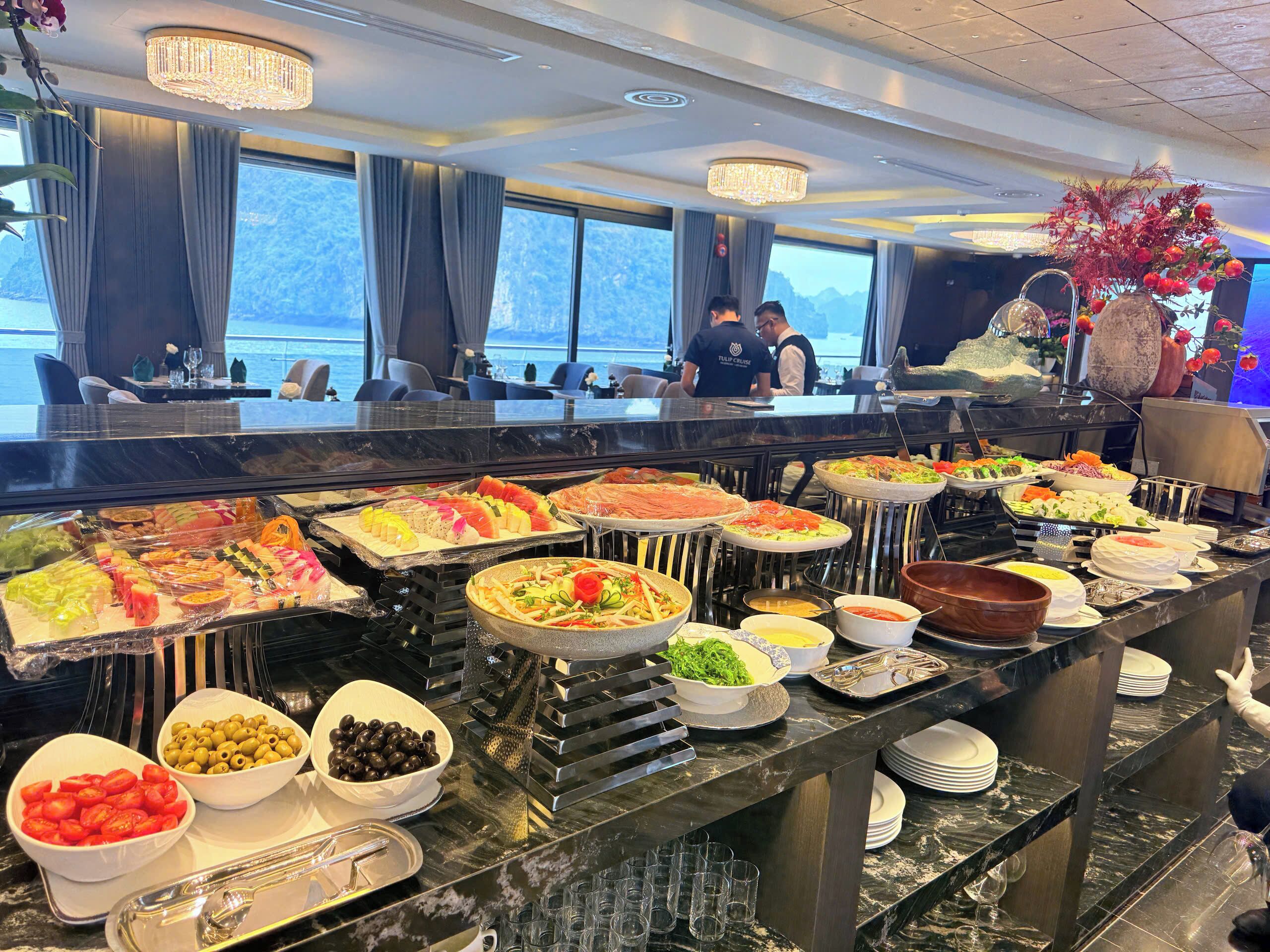 Un buffet proposant une variété de plats, avec une vue sur la mer grâce à de grandes fenêtres.