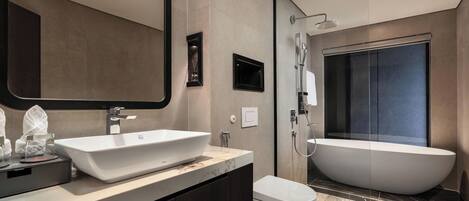 A modern bathroom with a large freestanding bathtub, a wall-mounted sink, and a toilet.