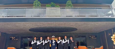A group of people standing in front of a hotel named 'Tulip Cruise' with a modern design and a sign that reads 'Ha Long Bay-Lan Ha Bay'.