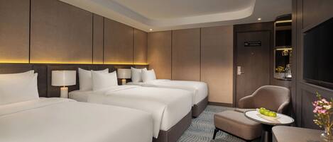 A hotel room with two beds, a small table with a vase, and a chair.