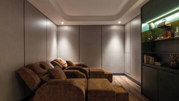 A modern room with a sectional sofa, built-in shelving with books and decorative items, and a wooden floor.