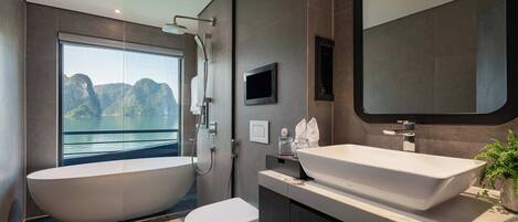 A modern bathroom with a freestanding bathtub, a large mirror, and a view of a mountainous landscape through a large window.