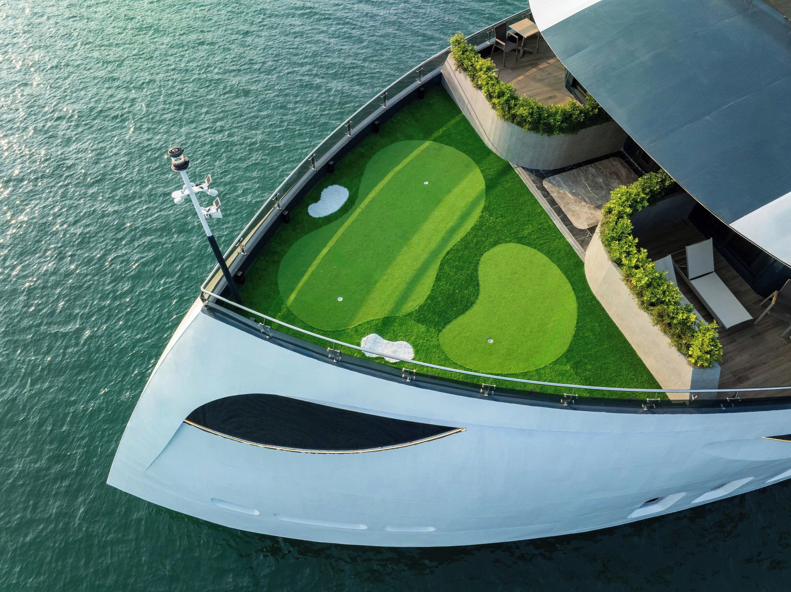 Vue aérienne d’un yacht doté d’un pont vert, d’une piscine et d’un espace de détente.