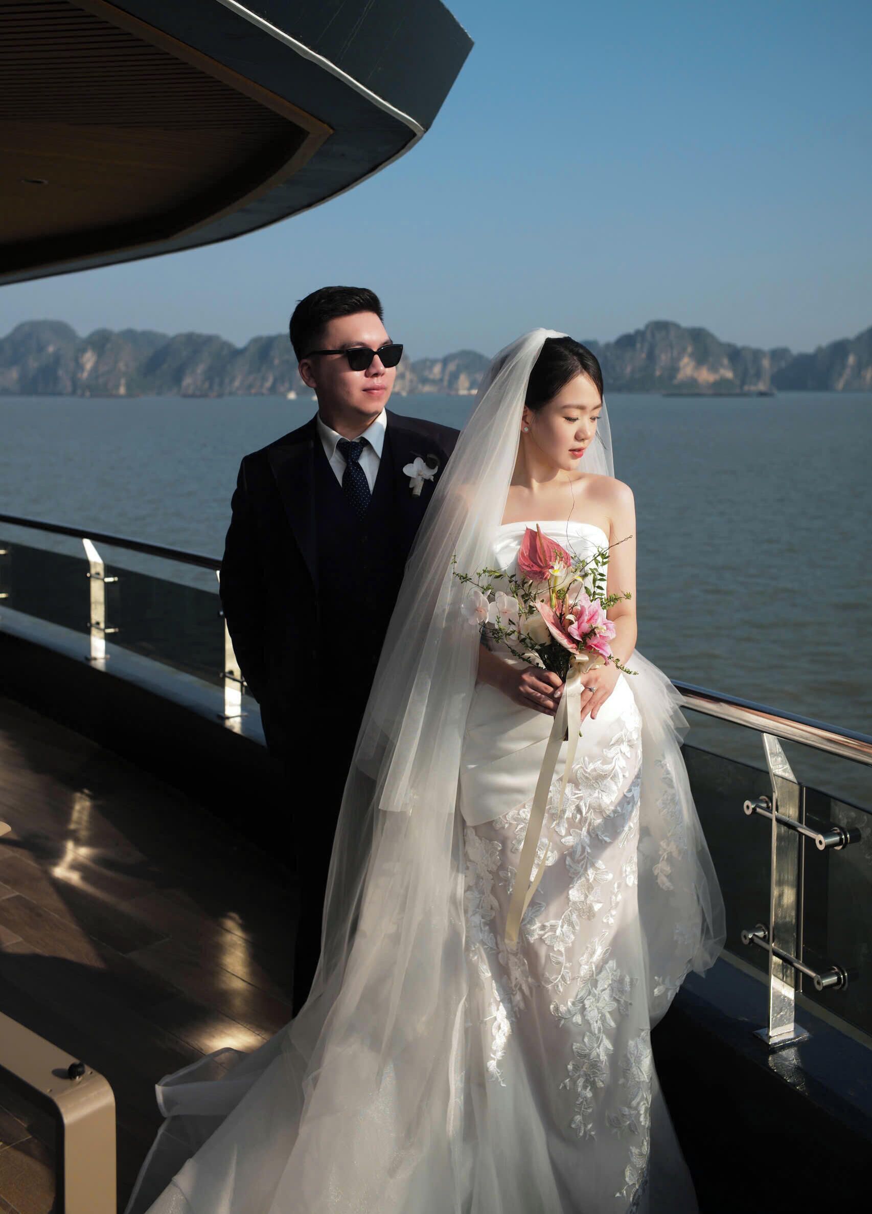 A couple on a boat with a view of a body of water and distant landforms.