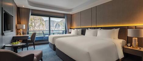 Een hotelkamer met een groot bed, een bureau met een lamp, een stoel en uitzicht op zee.