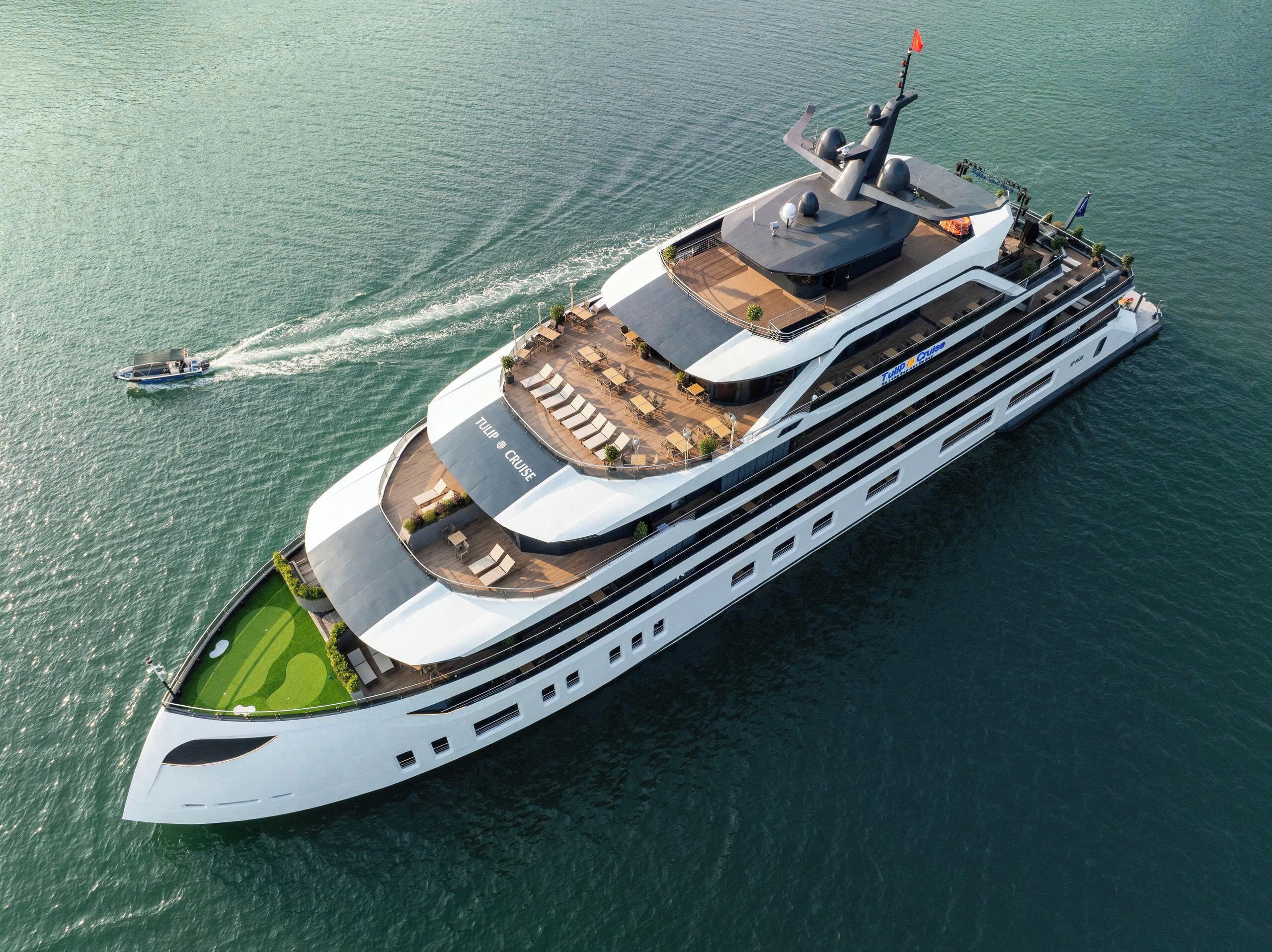 Un gran crucero moderno con varias cubiertas, incluyendo una terraza solárium con asientos al aire libre y un área techada con piscina.