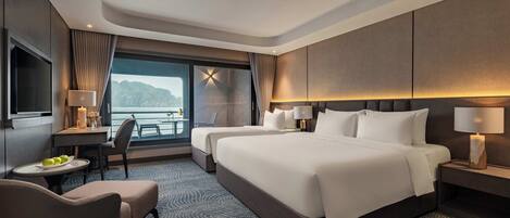Een hotelkamer met een groot bed, een bureau met lamp, een stoel en uitzicht op zee.