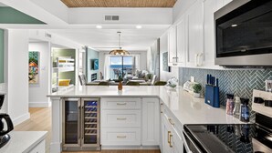 A modern kitchen with a central island, built-in appliances, and a large window overlooking a balcony.