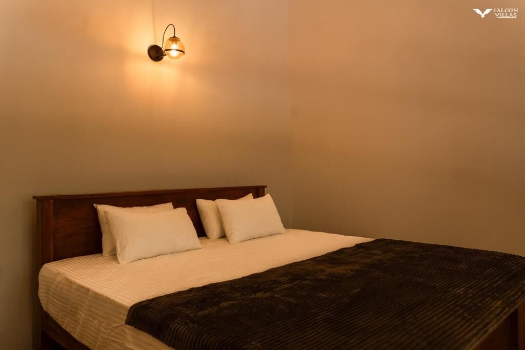 A neatly made bed with a wooden headboard, a white comforter, and two white pillows.