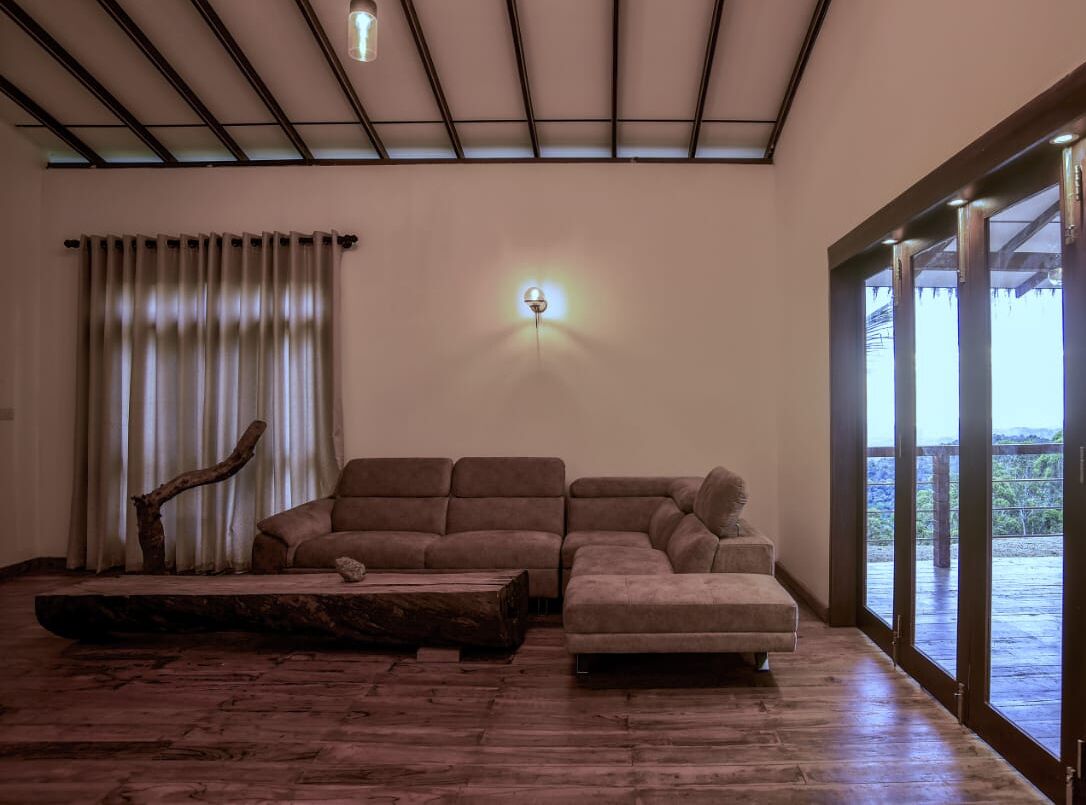 Un salon spacieux avec un canapé d’angle, une table basse et une grande fenêtre donnant sur un beau paysage.