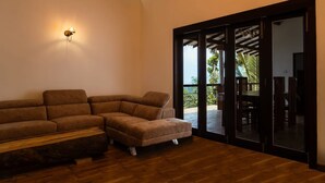 Una sala de estar con un sofá modular, una mesa de centro de madera y un gran ventanal corredizo que da a un espacio exterior.