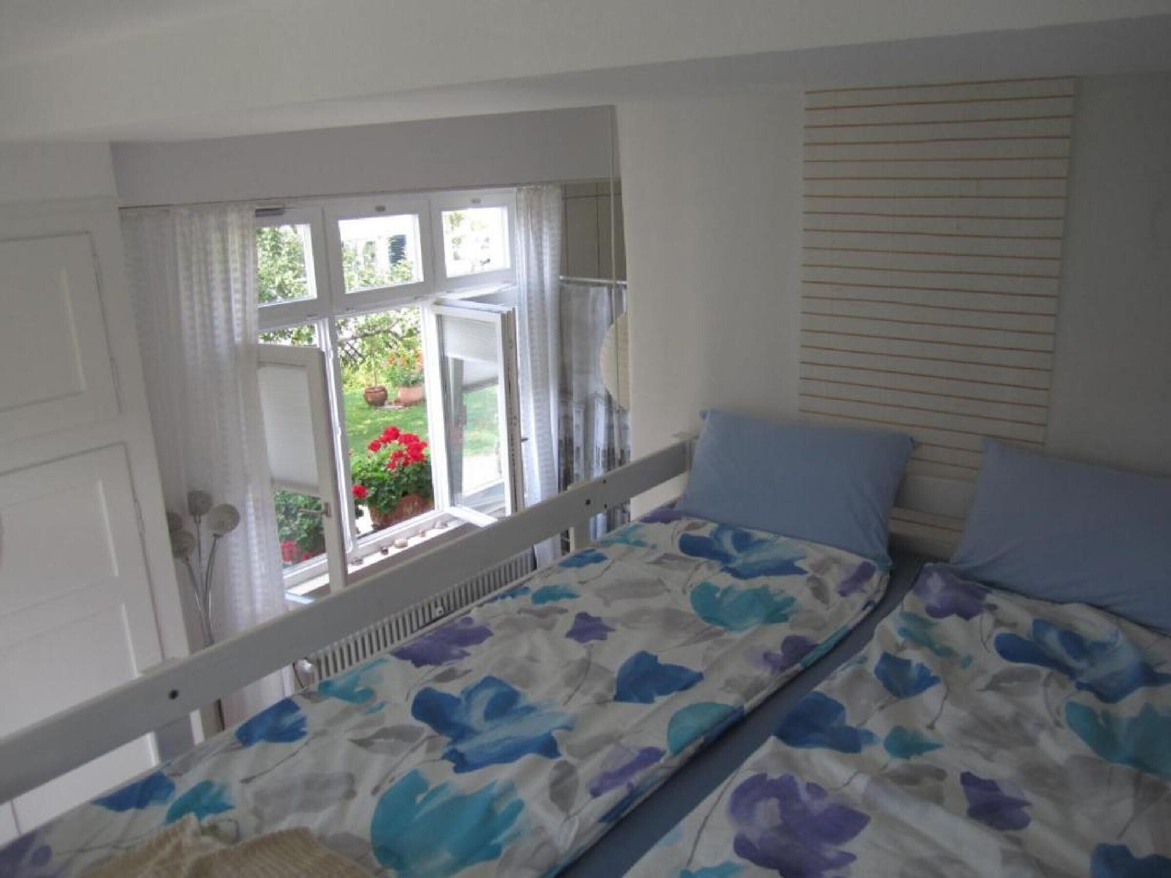 Une chambre à coucher avec un lit, une fenêtre avec des rideaux et une vue sur l’extérieur.