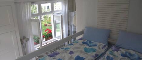 Une chambre à coucher avec un lit, une fenêtre avec des rideaux et une vue sur l’extérieur.