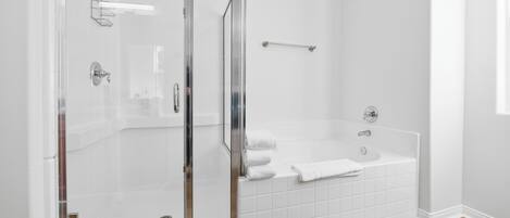 Een moderne badkamer met een douchecabine van glas, een wit bad en een houten vloer.