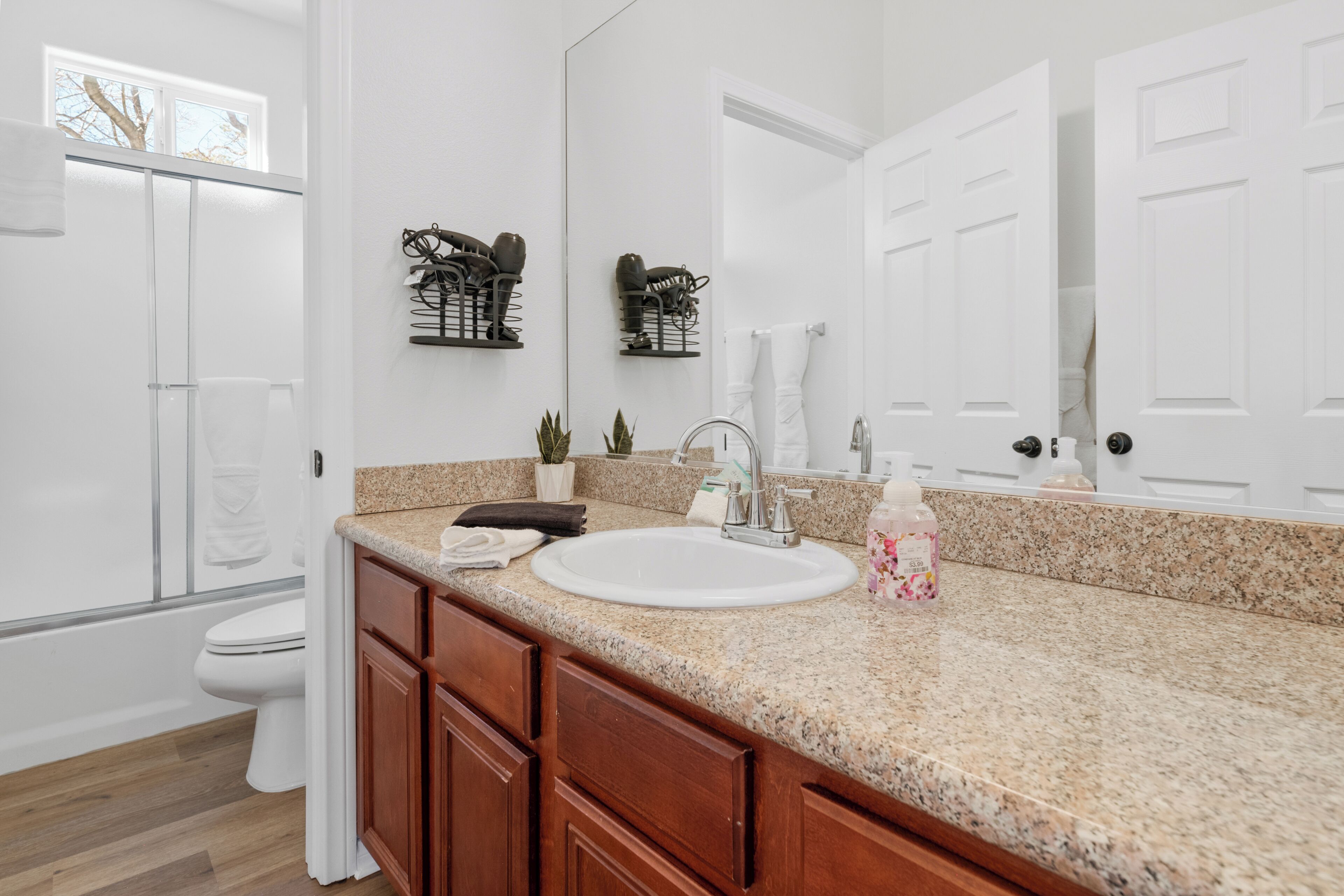 A bathroom with a white sink, wooden cabinets, a large mirror, and a towel rack.