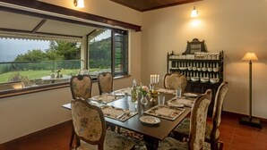A dining area with a table set for six, surrounded by floral-patterned chairs, a chandelier, and a view of the outdoors.