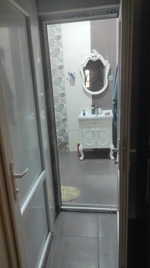 Une salle de bain avec un lavabo blanc, un miroir et des toilettes.