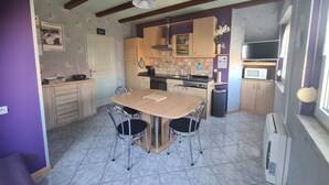 A kitchen with a wooden table, two chairs, and a microwave.