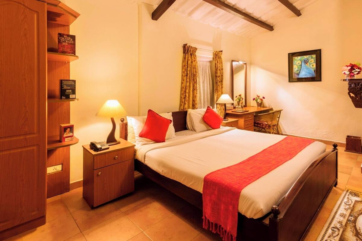 Une chambre d’hôtel comprenant un lit, des tables de chevet, un bureau, un miroir et une armoire.