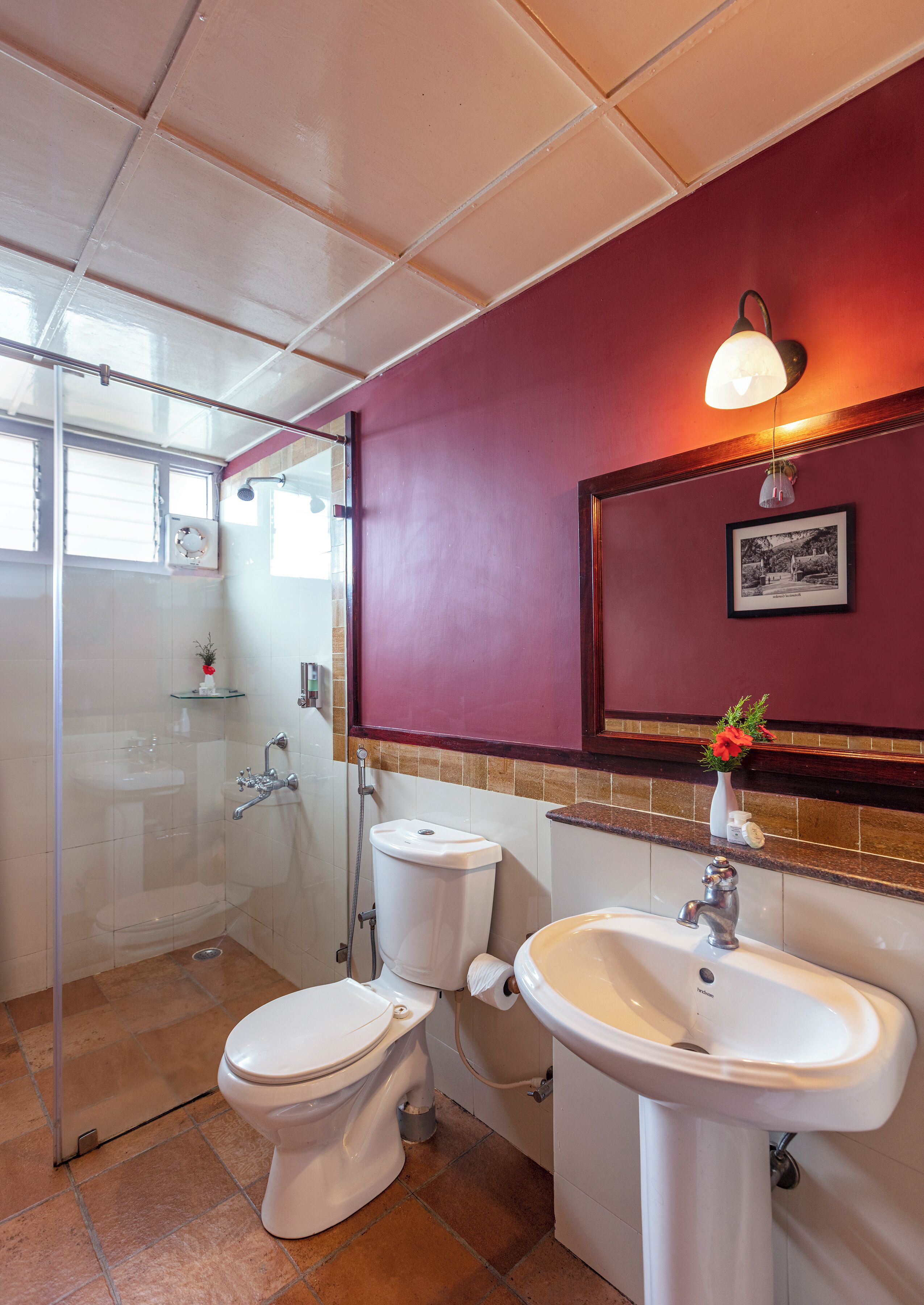 A bathroom with a glass-enclosed shower, a toilet, a sink, and a mirror.