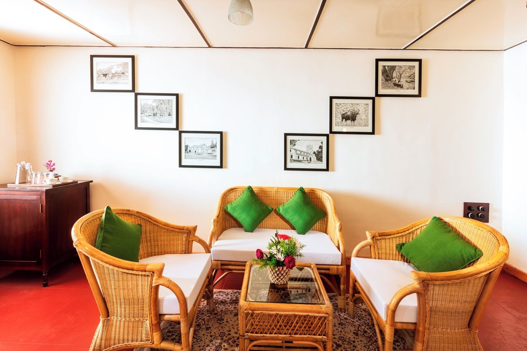 A room with wicker furniture, a glass coffee table, and a wall with framed black-and-white photographs.