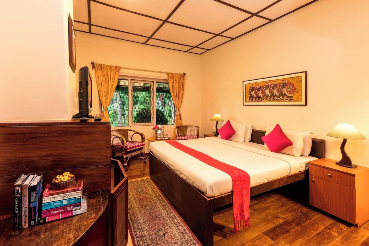 Une chambre d’hôtel avec un grand lit, une commode en bois, une petite table avec une lampe et une fenêtre avec des rideaux.