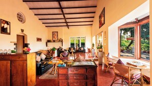 A spacious living area with a wooden coffee table, leather sofas, and a dining area with wicker chairs.