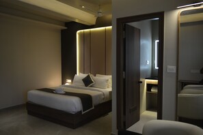 A modern hotel room with a large bed, bedside tables, a wardrobe, and a ceiling fan. - hotel muthahalli grand (Bengaluru)