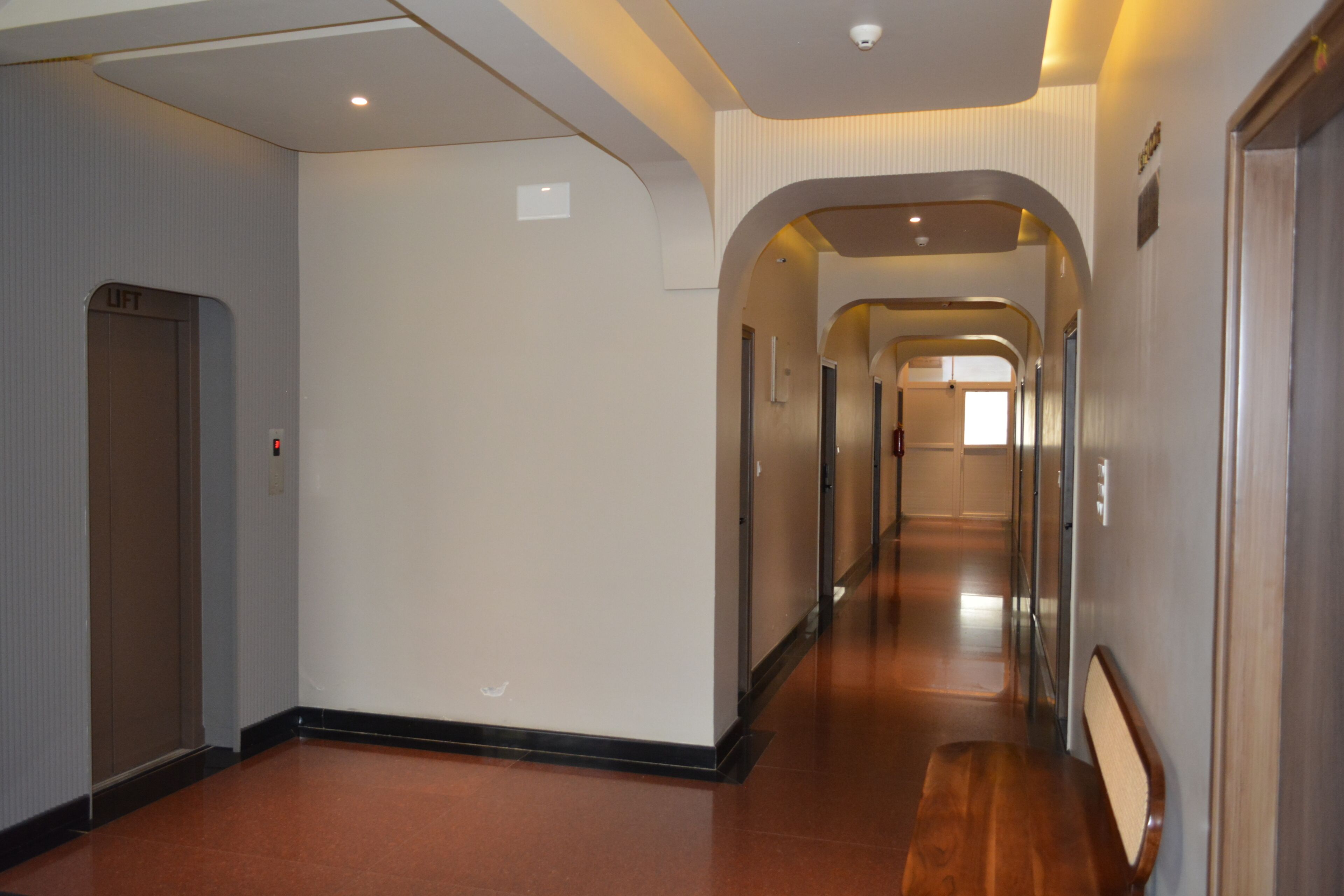 A hotel corridor with a wooden floor, white walls, and a series of doors.