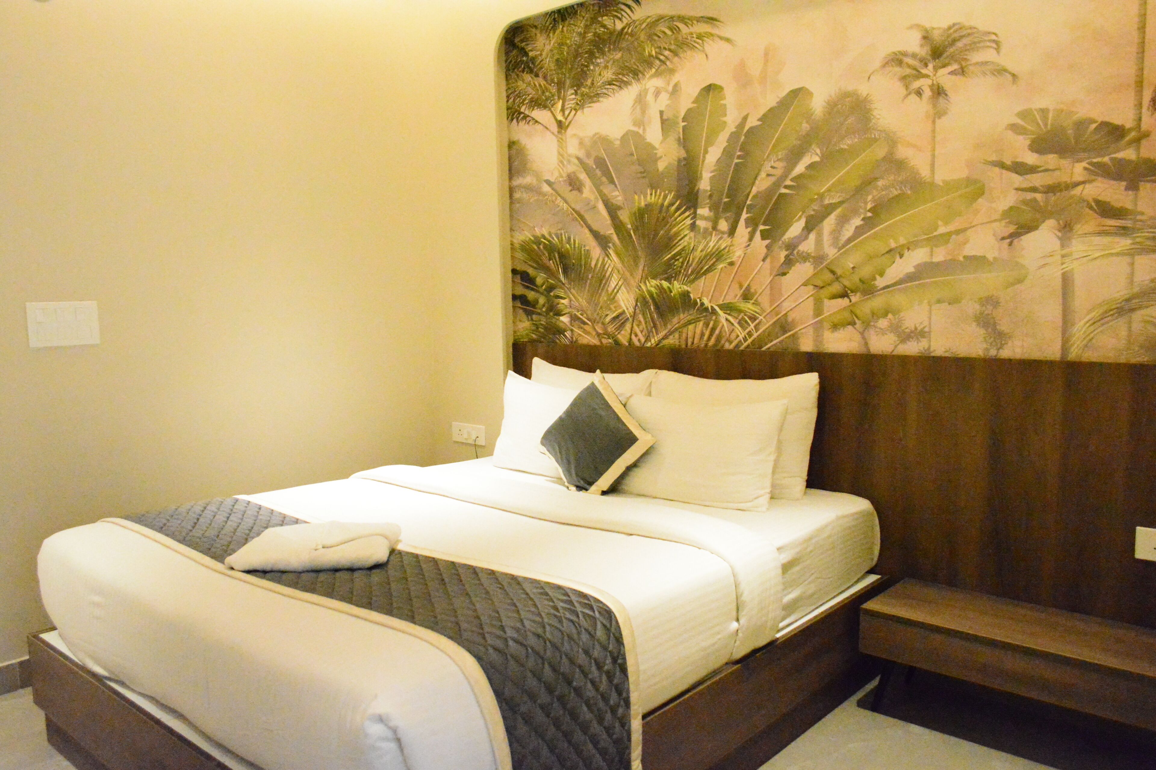 A neatly made bed with a quilted blanket, a pillow, and a bedside table with a lamp.
