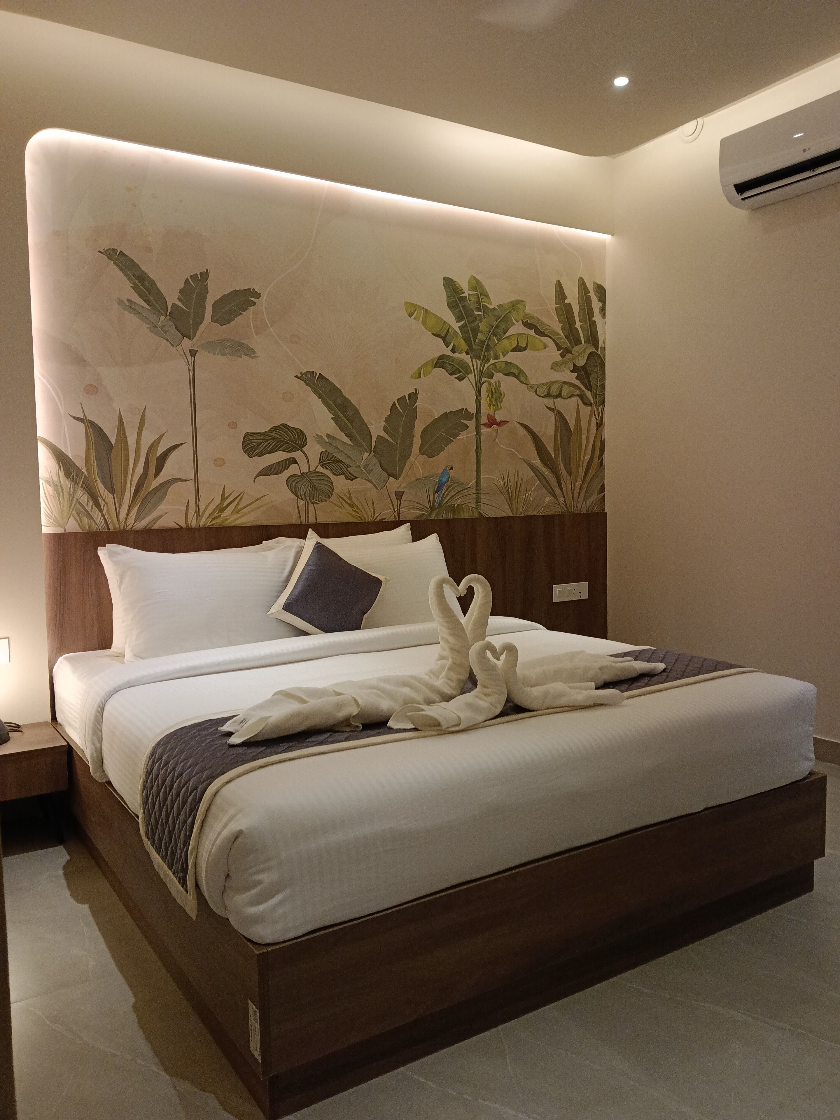 Ein ordentlich bezogenes Bett mit weißen Leinen und zwei Kissen, eine Wand mit einem botanischen Wandbild und ein hölzernes Kopfteil.