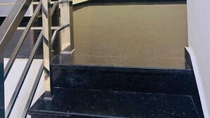 A staircase with a black marble finish leading to a landing with a ceiling fan. - Chandan Palace (Agra)