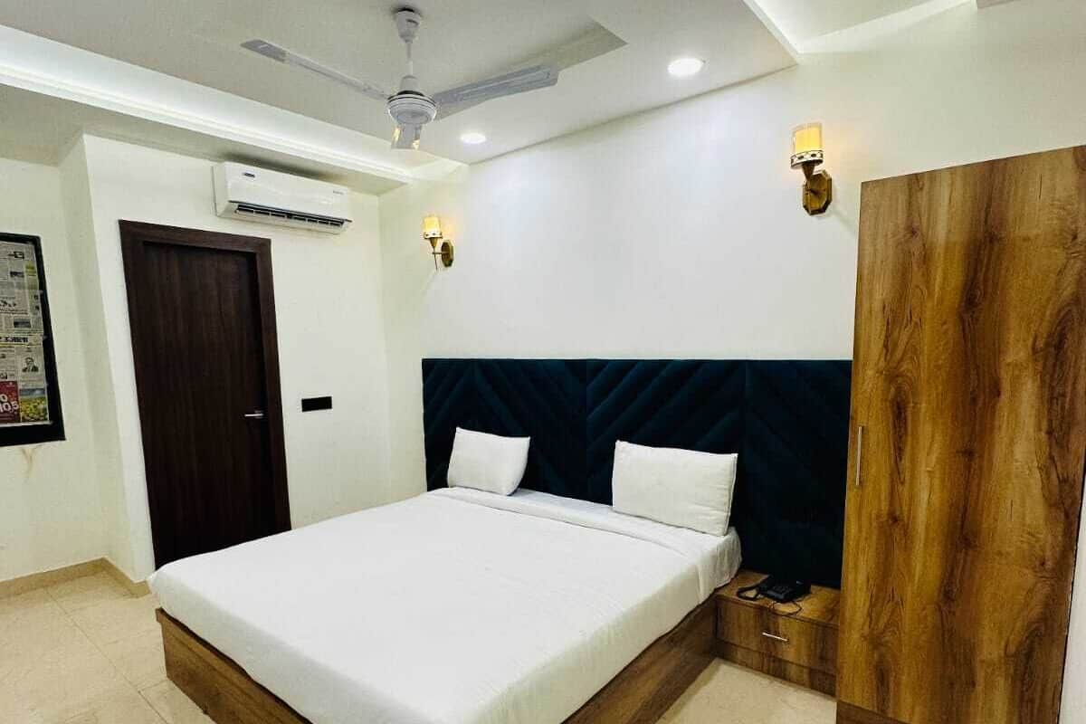 Un dormitorio moderno con una cama grande, ventilador de techo, unidad de aire acondicionado y armario de madera.