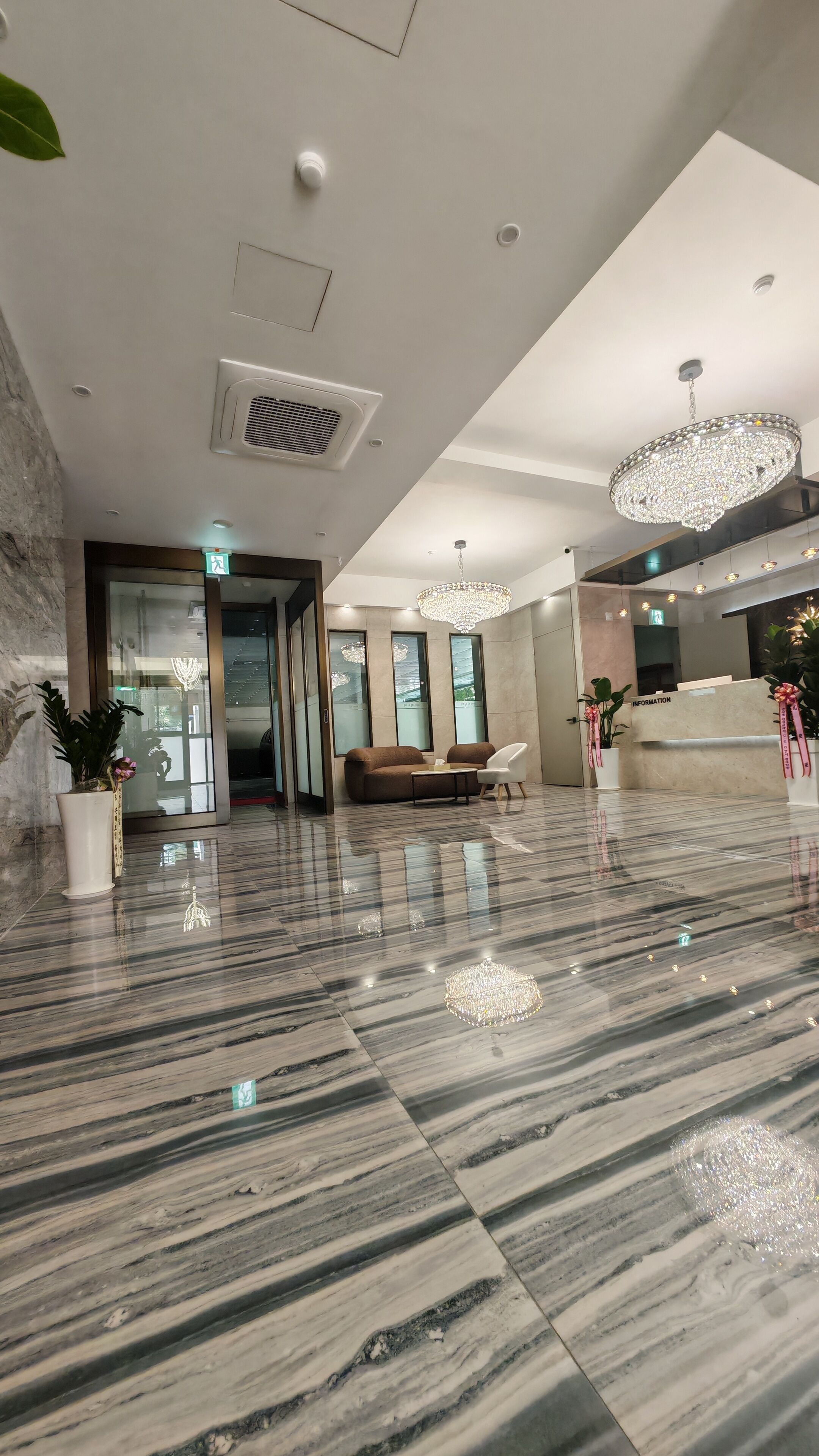 A modern lobby with a marble floor, a reception desk, and a seating area with a sofa and chairs.
