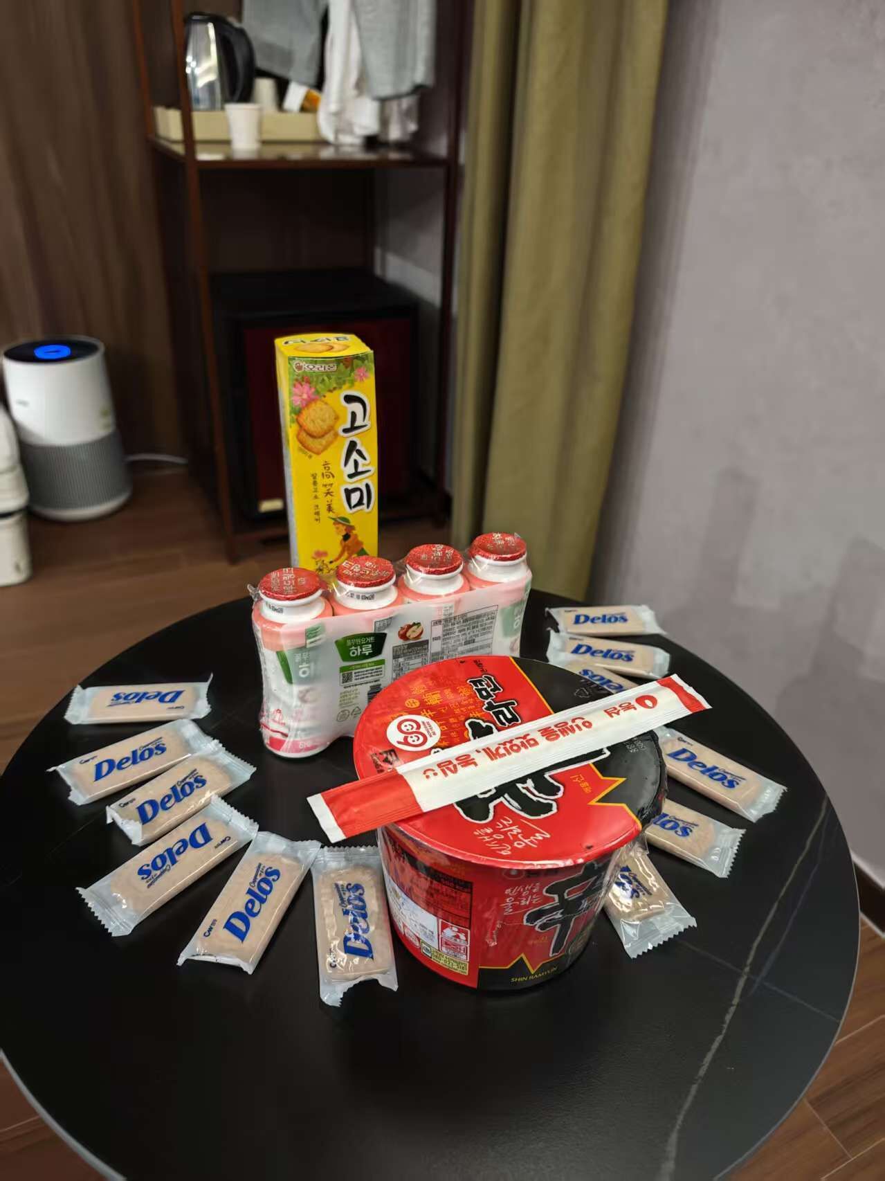 A table with various food items including a can of soup, bottles of drinks, and packets of snacks.