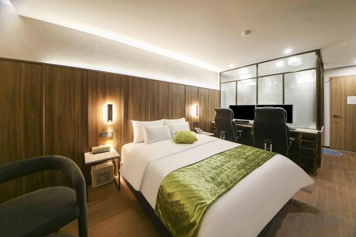 A hotel room with a bed, desk, chair, and a nightstand.
