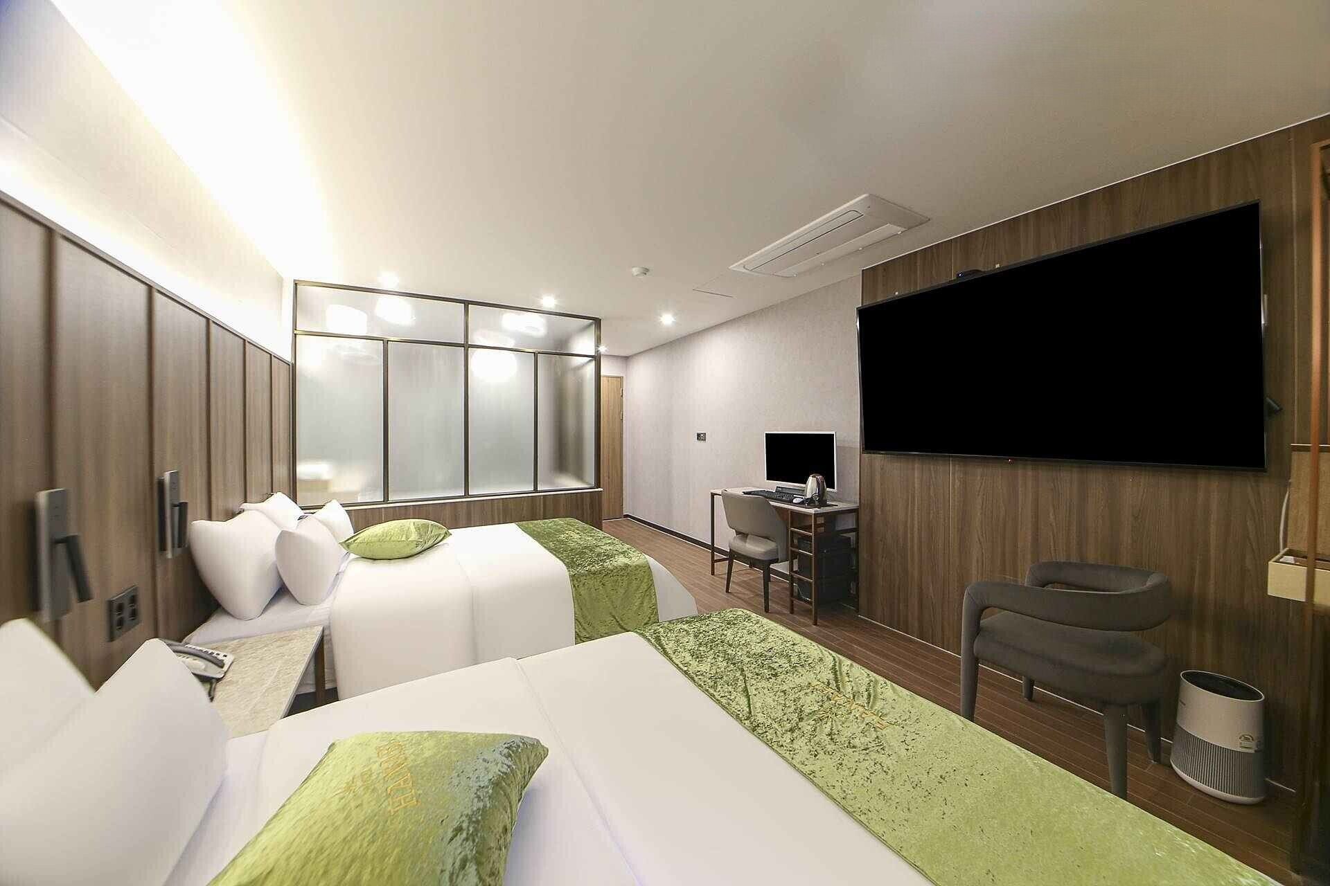 Una habitación de hotel moderna con una cama grande, un escritorio, una silla, un televisor y un armario.