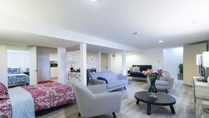 Una sala de estar moderna con un sofá, un sillón y una mesita con un jarrón de flores.
