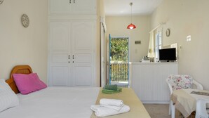 Quarto com cama, escrivaninha, cadeira, televisão e varanda com vista.